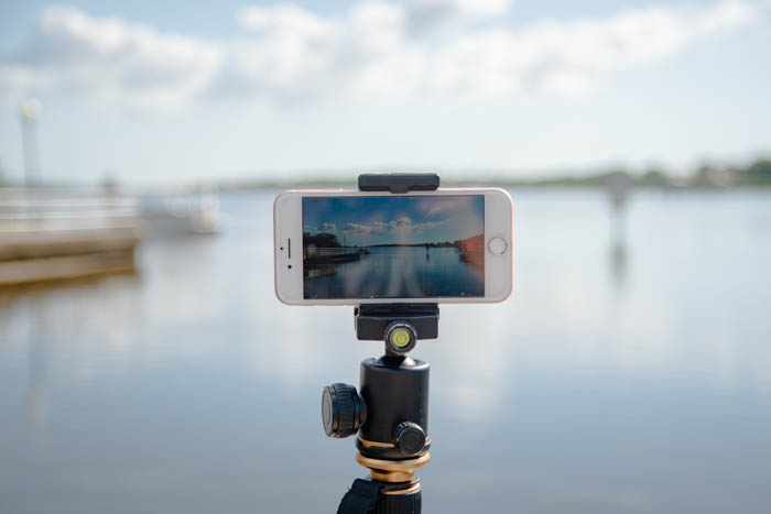 An iPhone setup on a tripod mount to take a picture of a waterfront scene