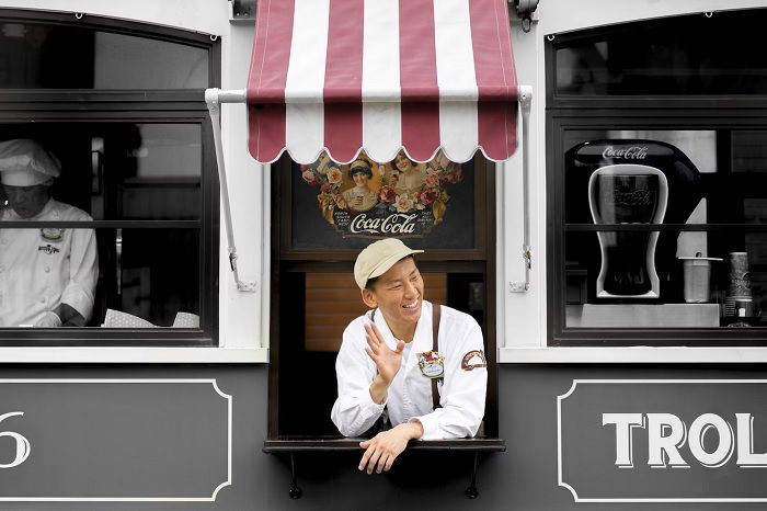 Man leaning out of a window waving to people out of shot