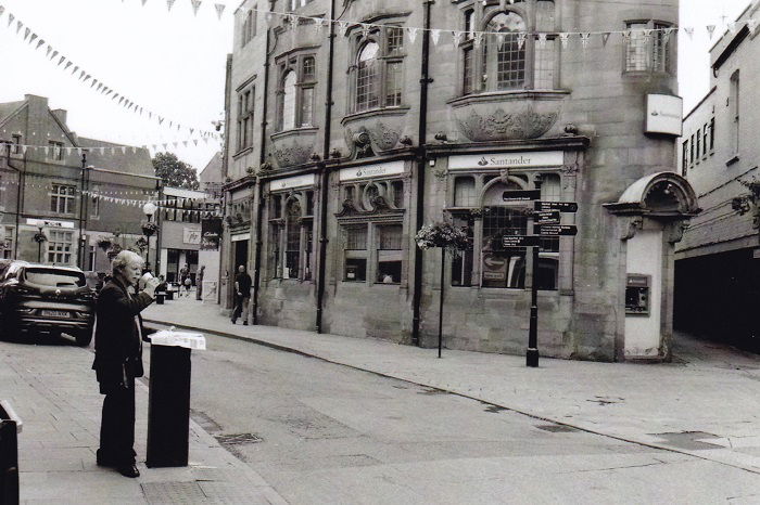 Man drinking a coffee in the street outside Superdrug in Oswestry town centre