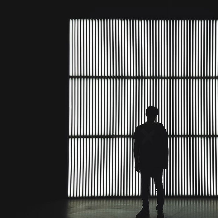 Black and white photo of man standing in front of a grated window