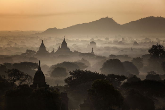 Photo of the silhouette of a temple with mountains in the background