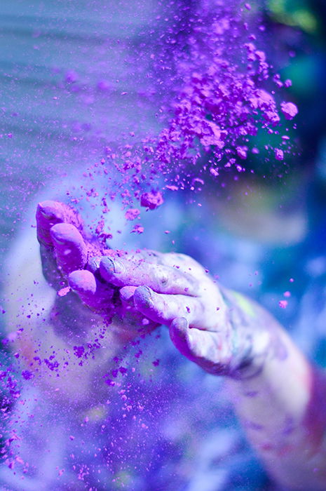 Close-up photo of a pair of hands throwing purple color powder