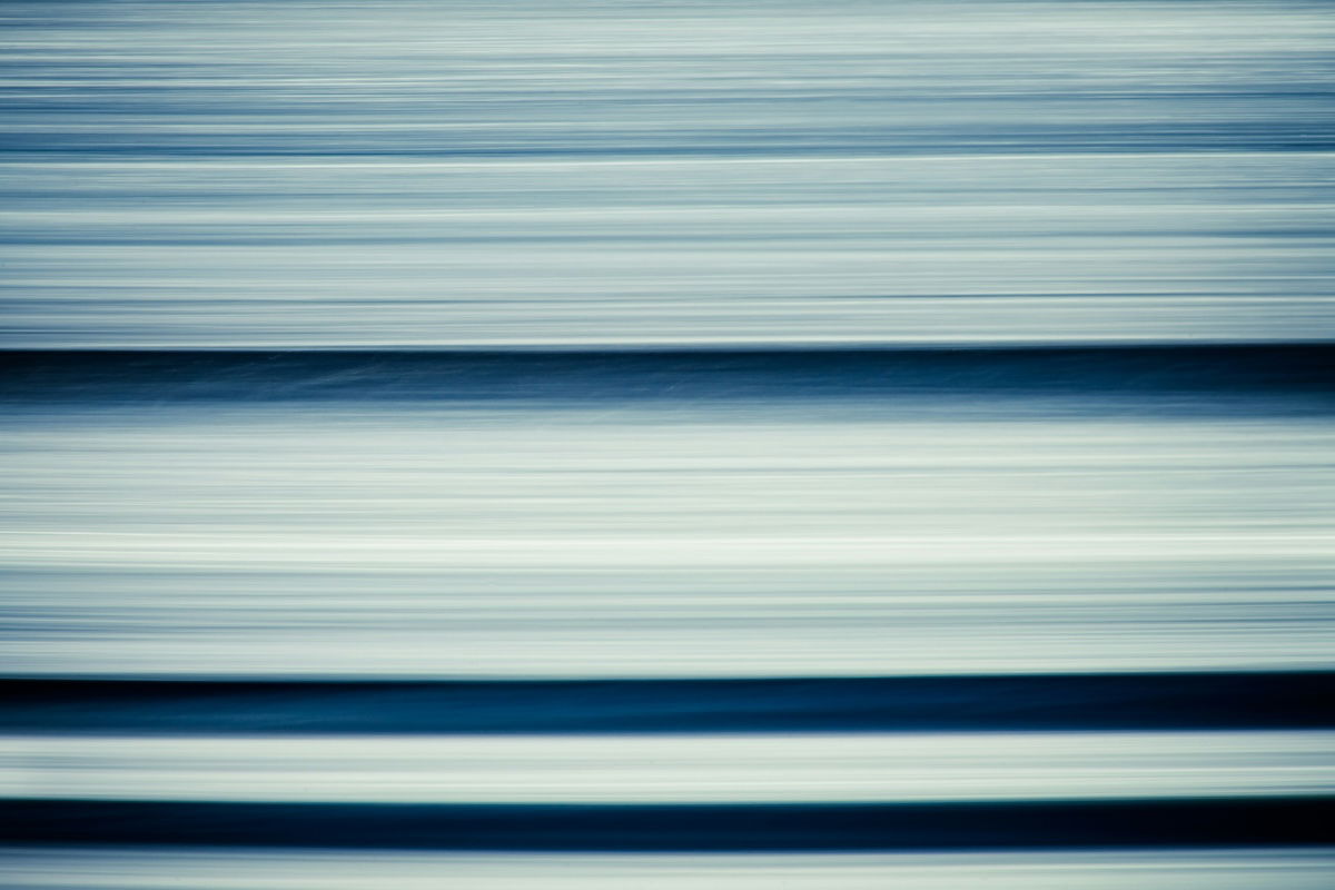 Abstract blue lines created by waves and shadows using horizontal intentional camera movement