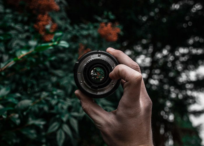 a person holding a pancake lens outdoors