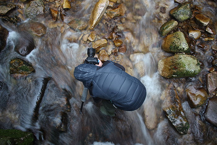 a high angle photo of a photographer setting up gear for taking waterfall photography 