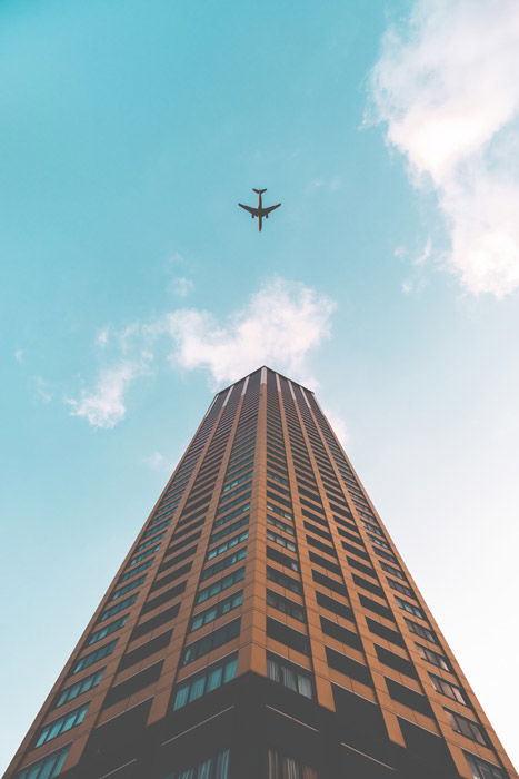 Photo of an airplane and a tall building from an upward-facing perspective