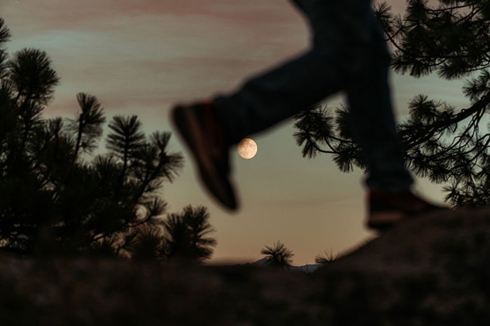 Photo of the silhouette of a man running with the moon sharp in the background