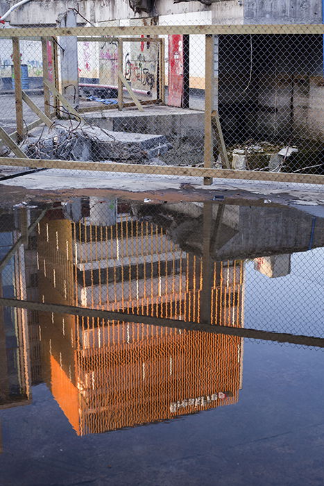 Photo of a tall building reflecting in a puddle on the street