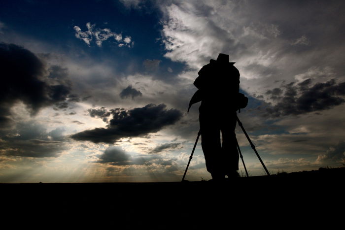 A silhouette of a photographer with a tripod