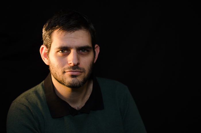 Portrait photo of a man against a dark background using split lighting