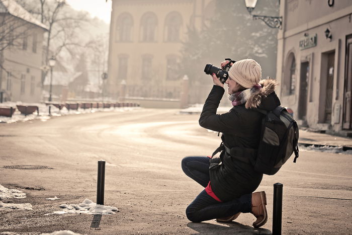 a female photographer shooting a street scene on a DSLR