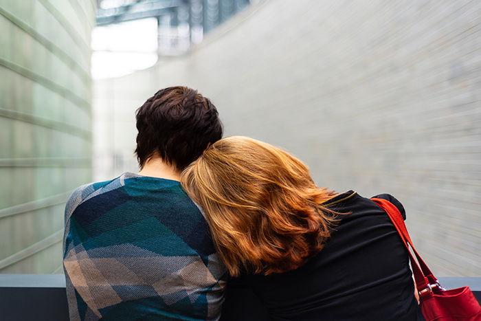 a portrait of the back of two women leaning on each other