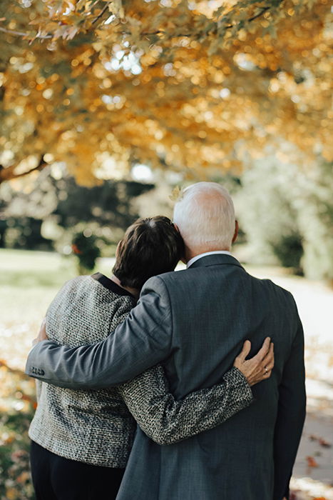 the back of an elderly couple at a funeral 