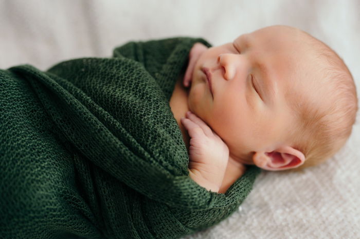 Close-up photo of a newborn baby swaddled in a blanket