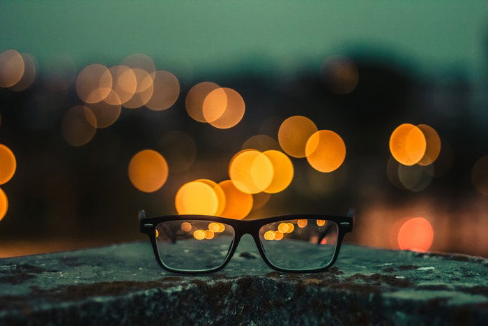 a pair of glasses on a wall, bokeh lights in the background