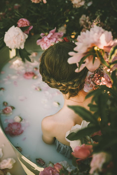 A girl in a bathtub surrounded by beautiful flowers 