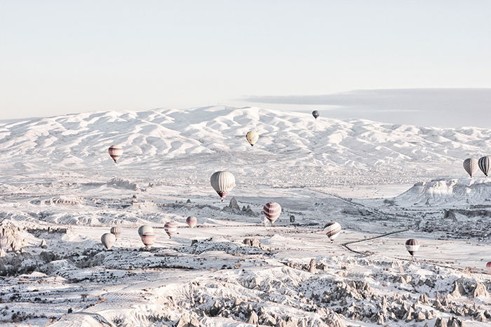 Hit air balloons floating over a snowy landscape 