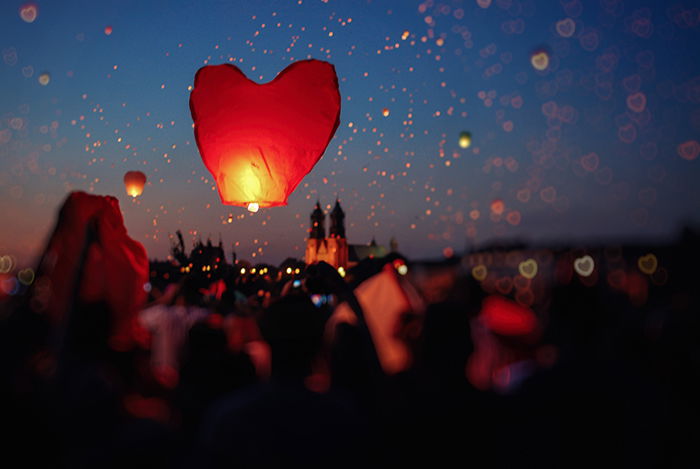 A heart shaped lantern floating into the night sky