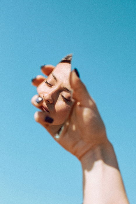 A hand holding a fragment of a mirror with a girls face reflected in it 