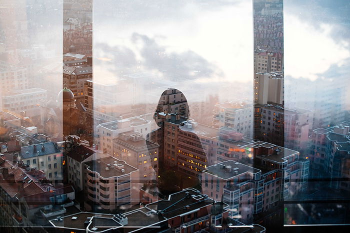 Photo of the silhouette of a woman reflecting on the window of a skyscraper