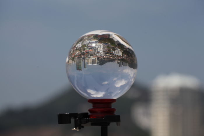 a lensball on a tripod, reflecting a sprawling cityscape