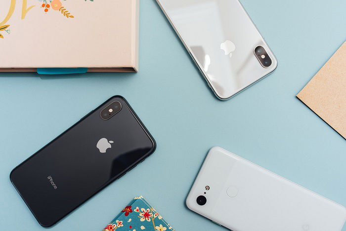 Three Apple iPhone cameras on top of a desk shot from above