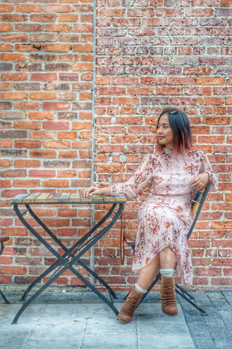 Photo of a woman sitting in front of a brick wall