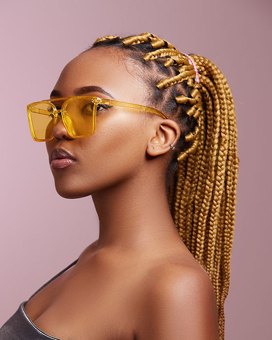 Portrait photo of a woman with yellow glasses and braided hair