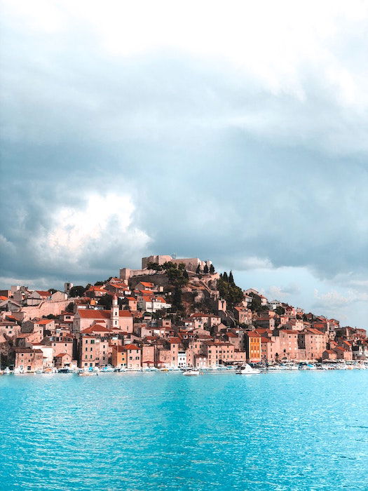 Landscape image of an island with contrasting blue sea and moody skies 