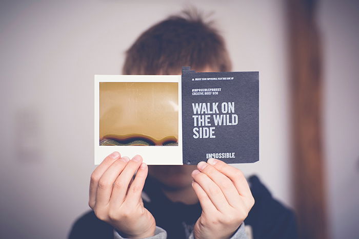 Photo of a man holding a Polaroid picture in front of his face