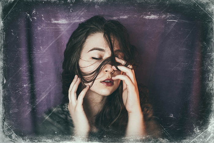 A girl posing in front of a purple backdrop 