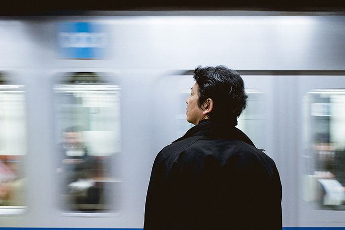 a Japanese man waiting for a train 