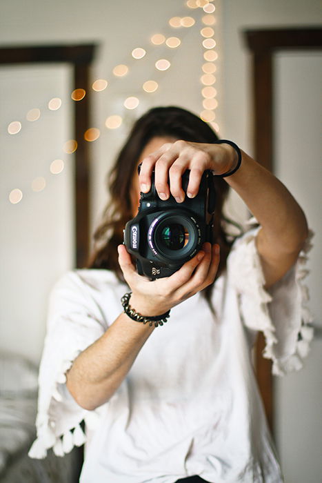 a female photographer holding a canon DSLR to the camera