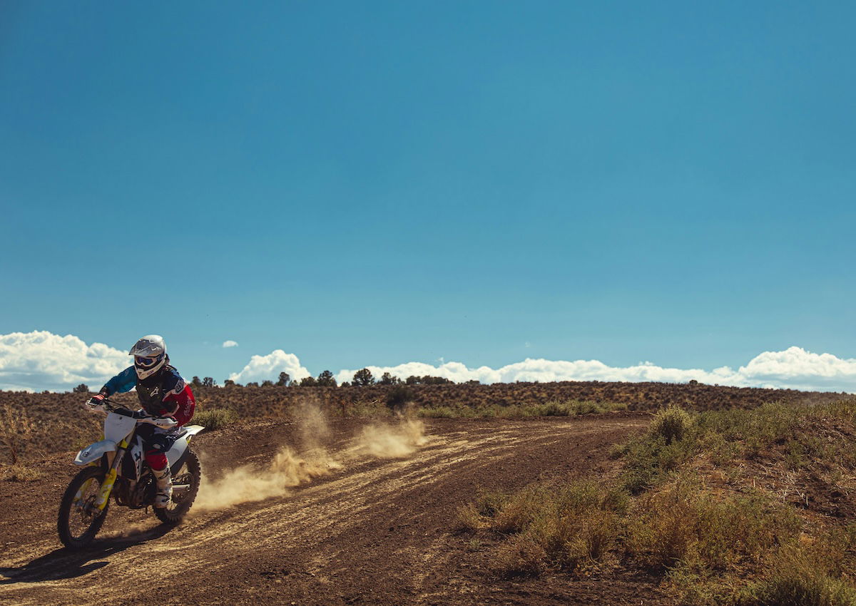 An asymmetrical composition of a motocross rider riding on a dirt track