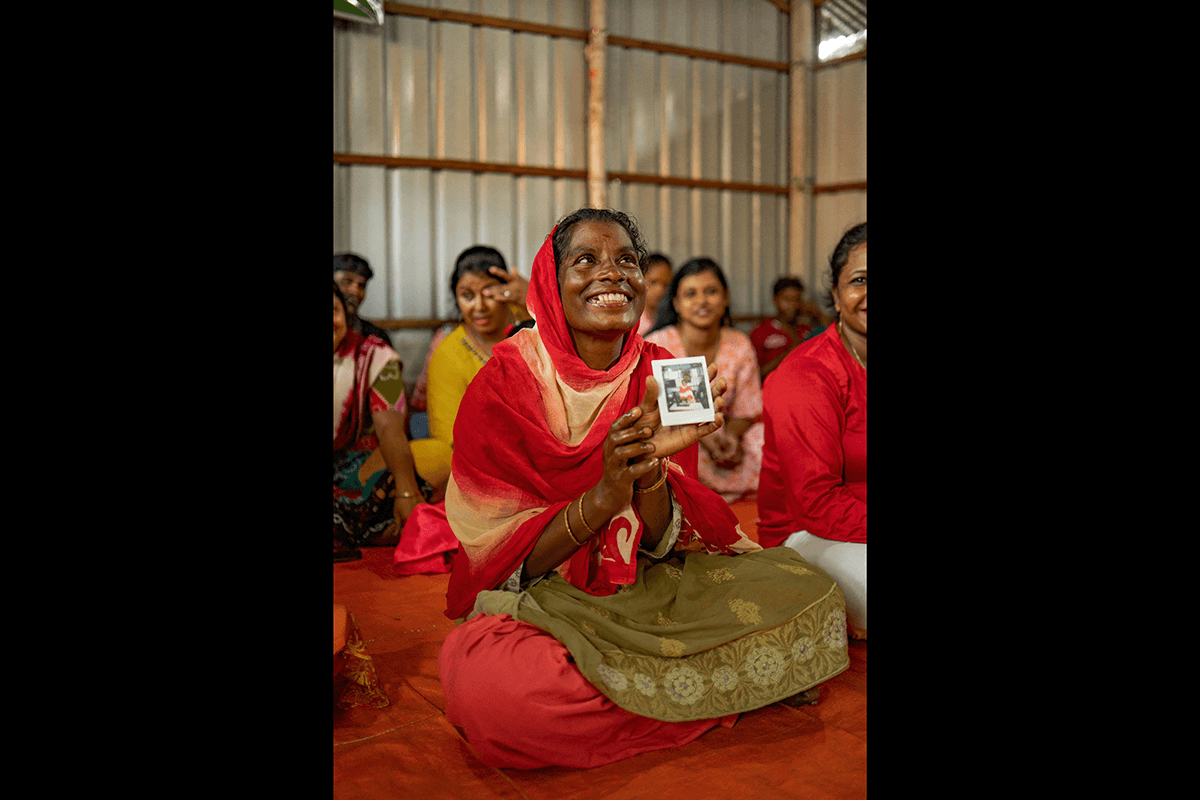 A photo of a woman smiling holding up a polaroid of herself as an example of photography style