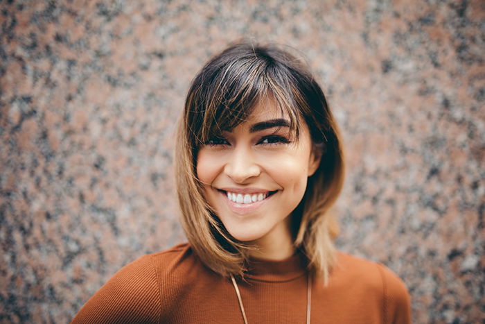 a professional headshot photo of a smiling young woman