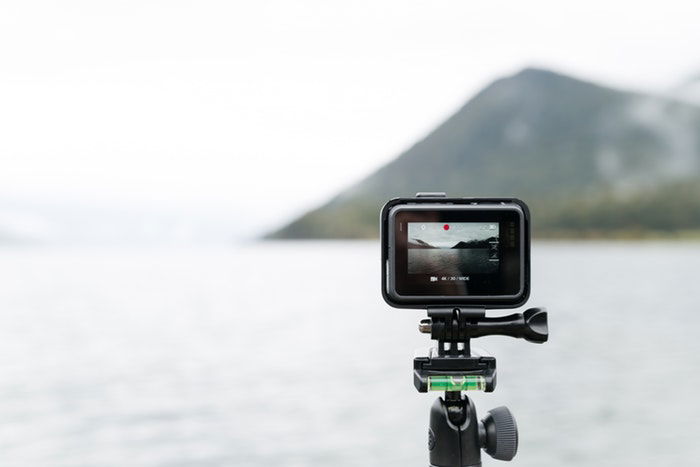 A GoPro on a tripod in front of a lake 