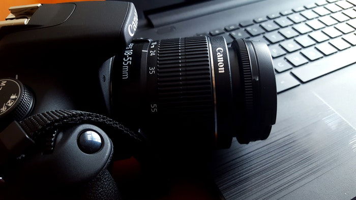 A canon camera on a desk with a keyboard