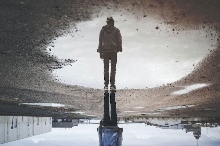 Forced perspective of a man standing in a puddle.