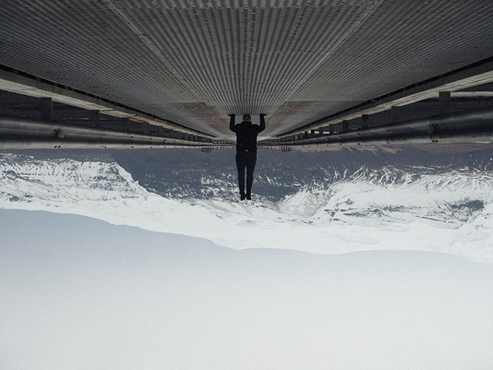 Model performing a handstand while illustrating forced perspective with a mountain behind.