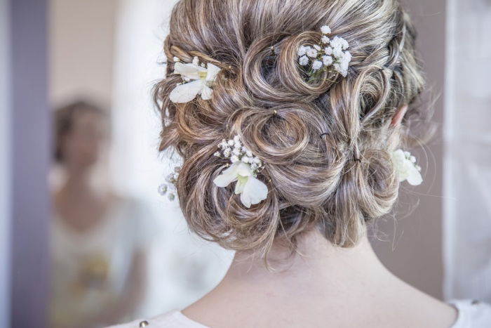 A close up of a wedding hair style with small flowers