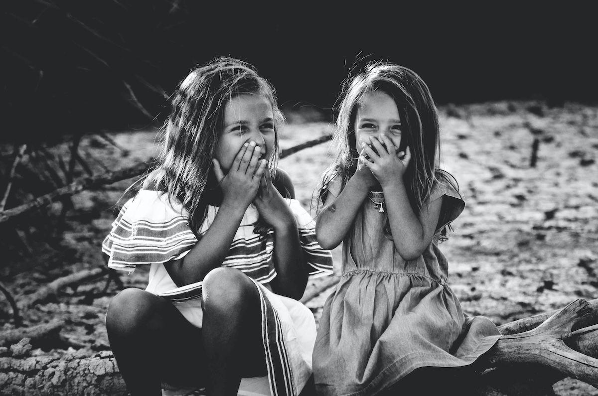 Black-and-white photo of two girls laughing for a kids photo pose