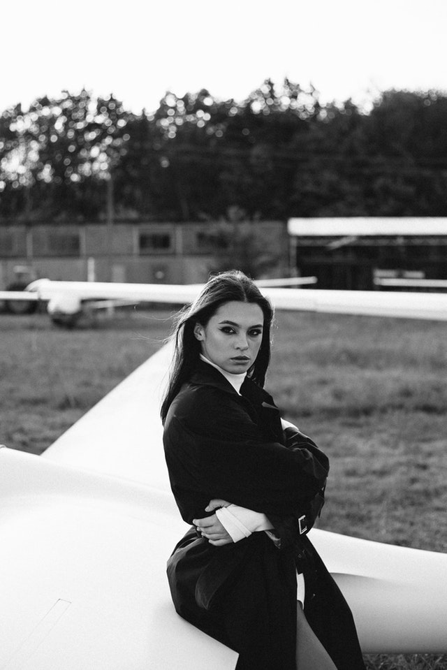 A black and white portrait of a female fashion model sitting on an airplane 