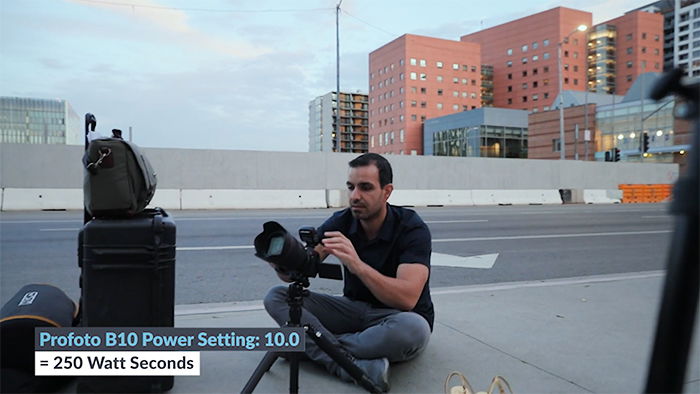 Photo of a guy sitting on a road setting up his camera