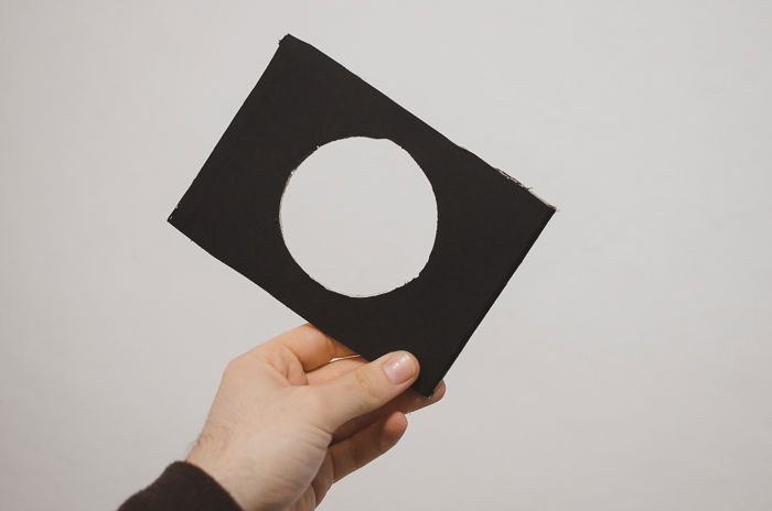 A person cutting cardboard to make a DIY phone projector