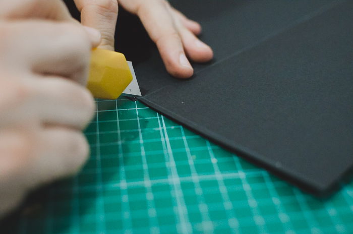 A person cutting cardboard to make a DIY phone projector