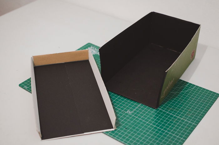 Gluing black paper to a shoe-box to make a DIY projector