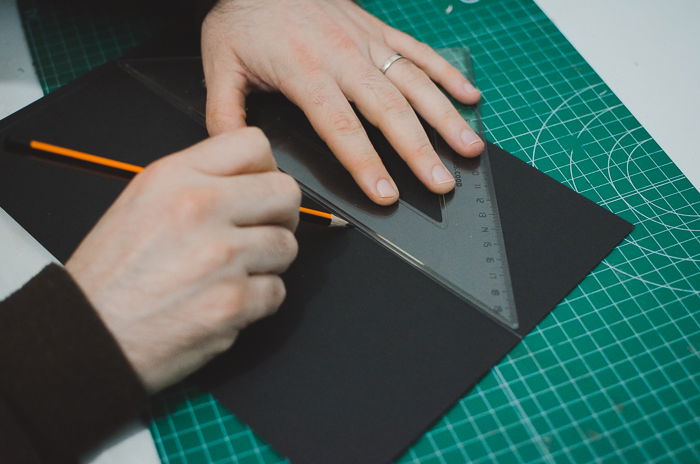 A person cutting cardboard to make a DIY phone projector