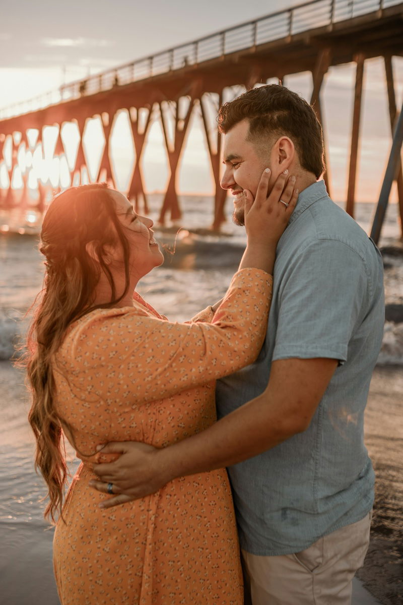 A woman holding a man's face with his arms wrapped around her for couple poses