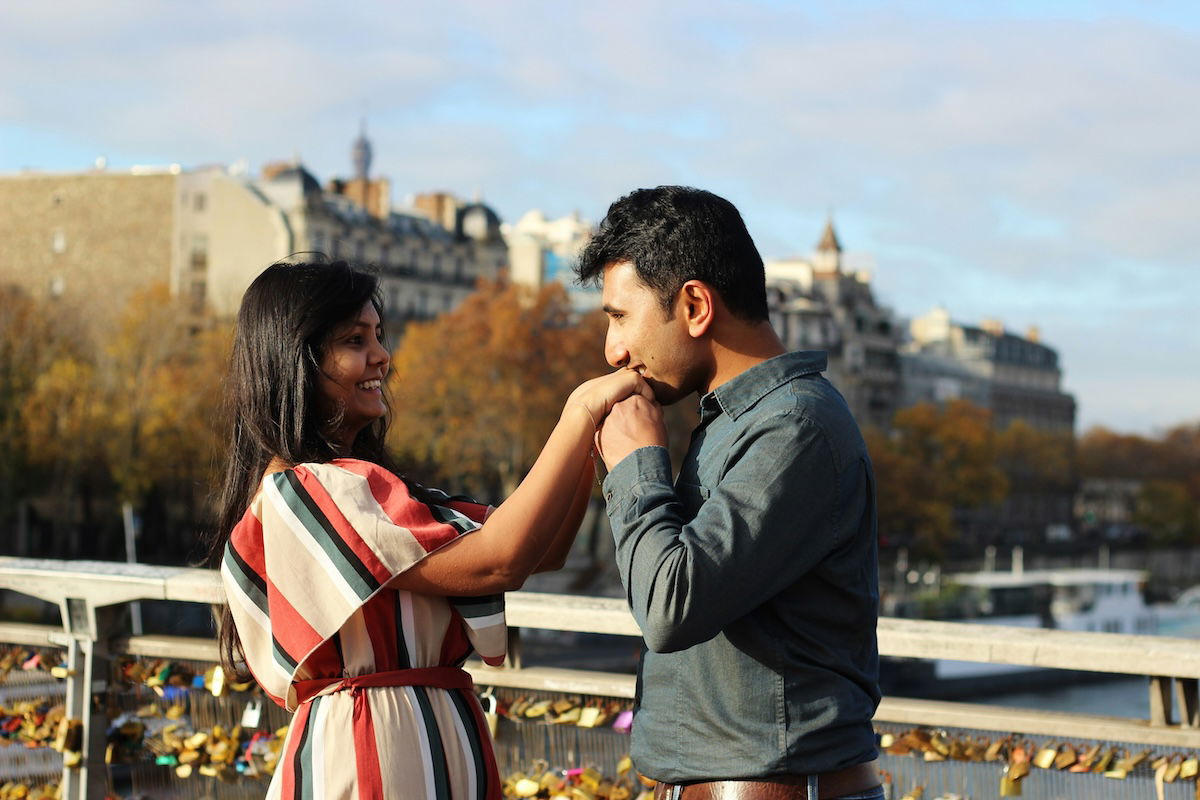 A man kissing a woman's hand on a bridge for couple poses